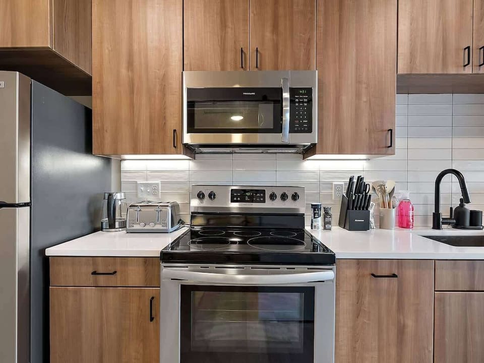 Fully equipped modern kitchen with stainless steel appliances and sleek wood cabinets.