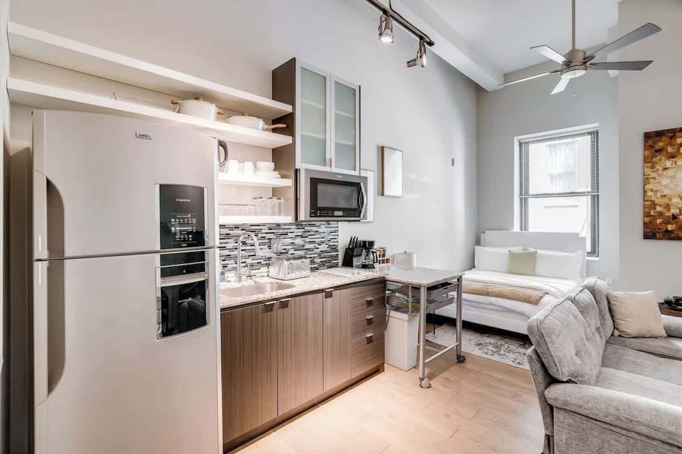 Bright studio with a sleek kitchen, cozy bed, and modern design for comfort.