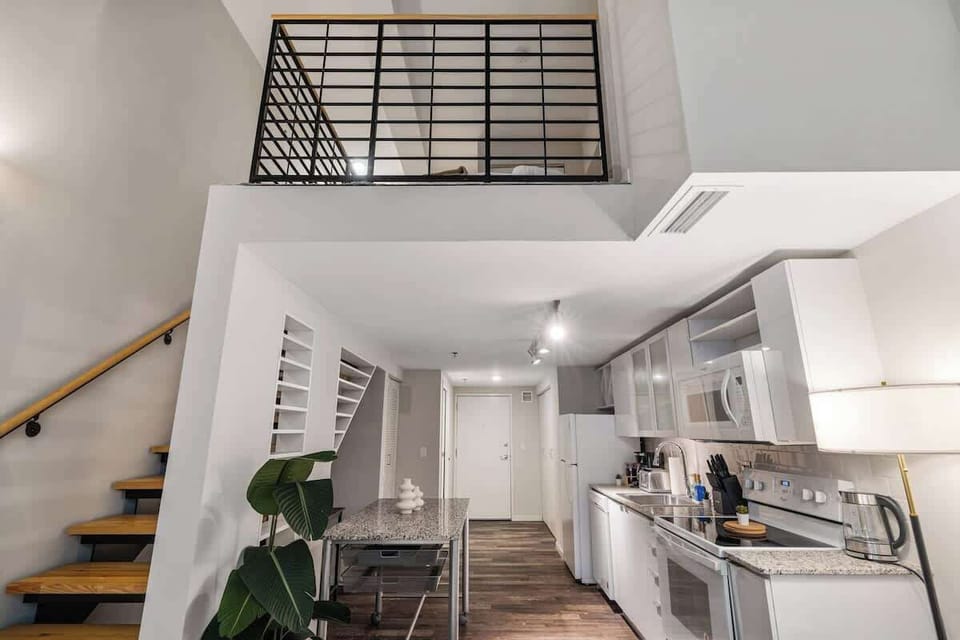 Stylish loft with a modern kitchen, open mezzanine, and sleek wooden staircase.