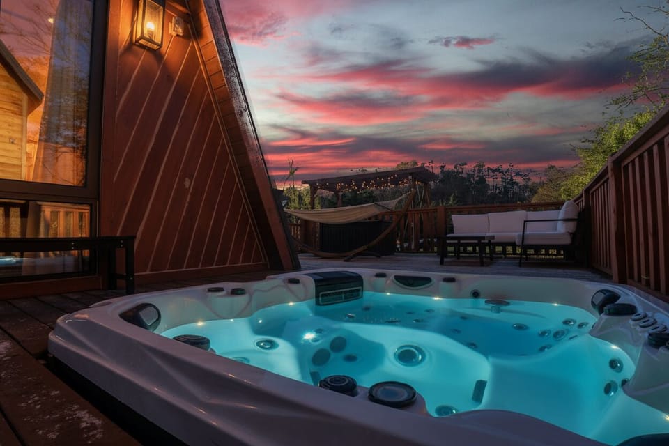 Private hot tub on the deck with sunset views over the Smoky Mountains. Unwind under the stars after a day on the lake — a romantic, family-friendly retreat with fire pit, pickleball, and Double A-frame charm.