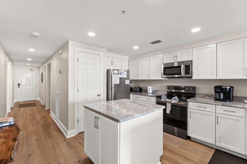 Spacious, fully updated kitchen with granite counters and bar seating opens into the main living area for effortless vacation living