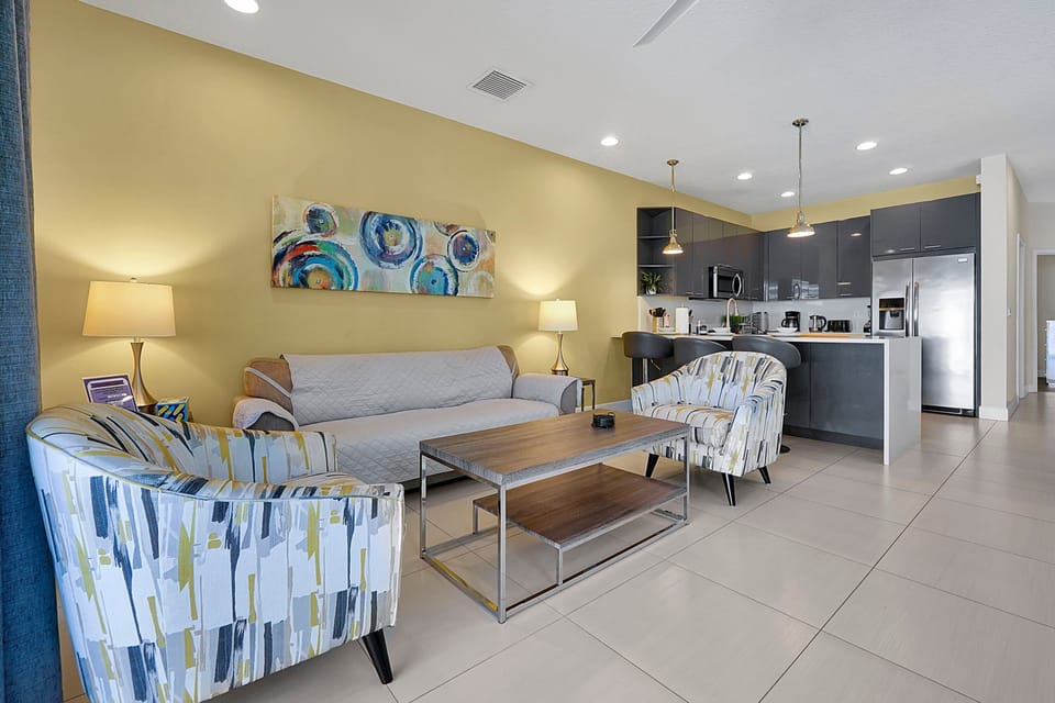This cozy, open-concept living area features stylish seating with a sofa and two accent chairs, perfect for relaxation.