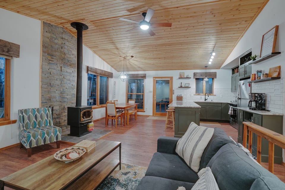 The living room features cozy seating, a TV, children’s games, & stunning views