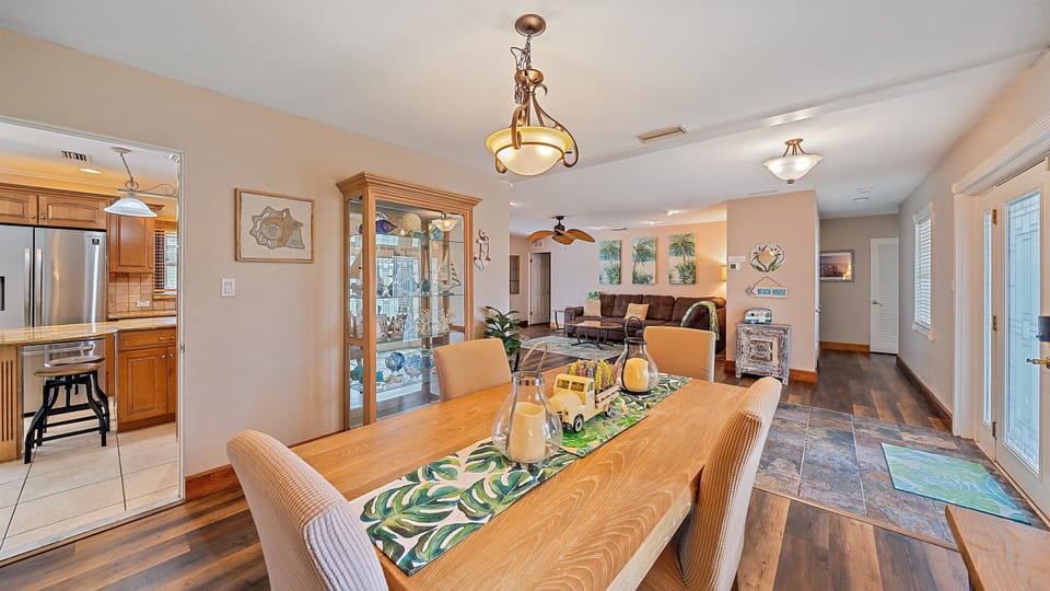 Gather for family meals in the welcoming dining area with coastal decor, offering a bright, seamless flow into the main living room and the kitchen.