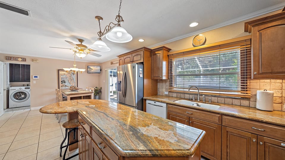 The beautifully appointed gourmet kitchen serves as the heart of the home, offering a large granite island and seamless access to both the casual dining area and in-home laundry.