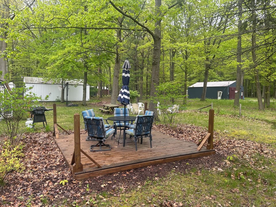 Patio with chairs, table, umbrella, and propane grill.