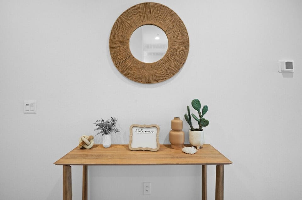 Minimalist console table w/ natural textures & soft decor for a calm first impression.