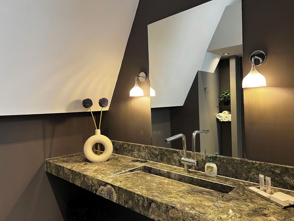 A stylish bathroom with a sleek stone countertop, modern fixtures, and warm lighting, accented by minimalist decor for a sophisticated touch.
