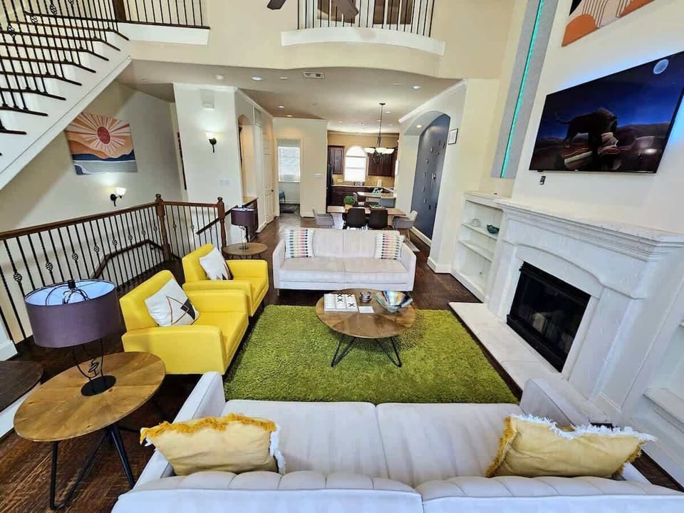 Grand living area with staircase and yellow seating arrangement.