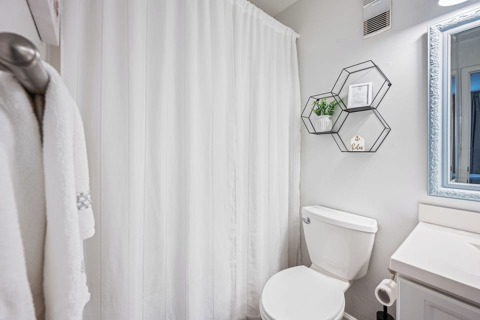 Enjoy the convenience of a private ensuite bathroom with a well-lit vanity, crisp finishes, and simple, coastal-inspired décor.