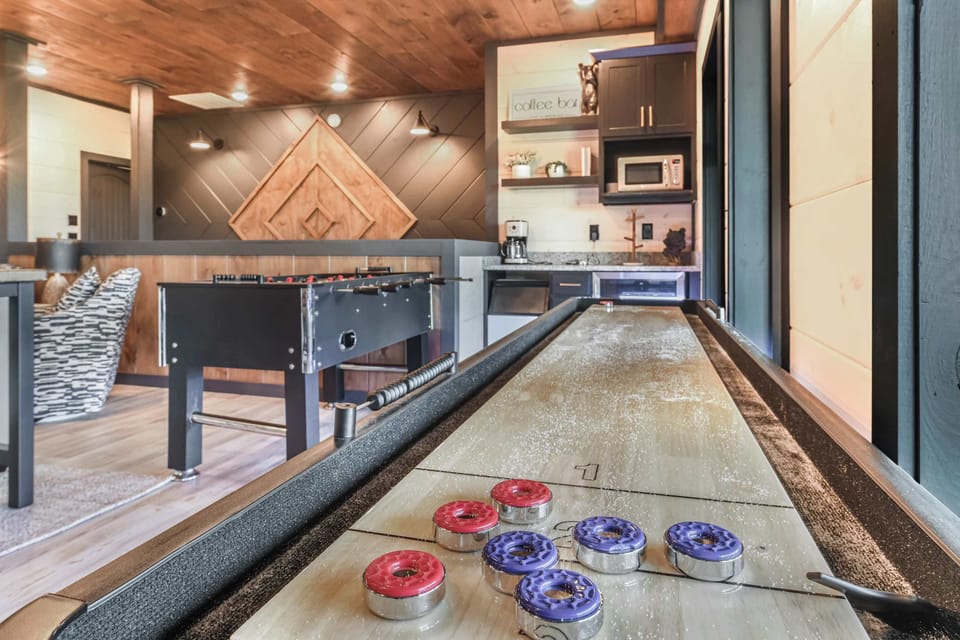 Game room with shuffleboard and foosball tables in a rustic setting.