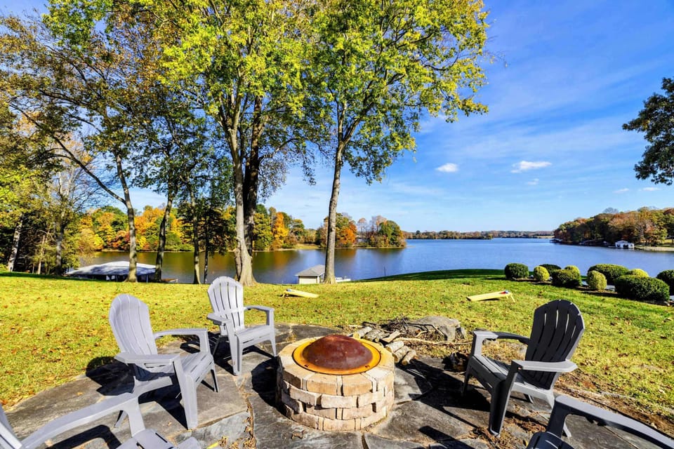 Cozy lakeside fire pit area with Adirondack chairs, offering stunning water views for relaxing evenings.
