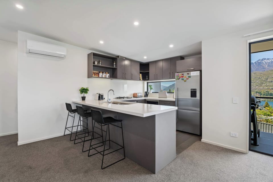 Bright kitchen space with island seating, modern design, and access to a scenic balcony.