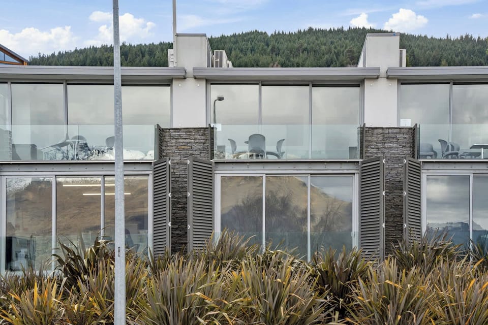 Glass-fronted apartments with mountain reflections.