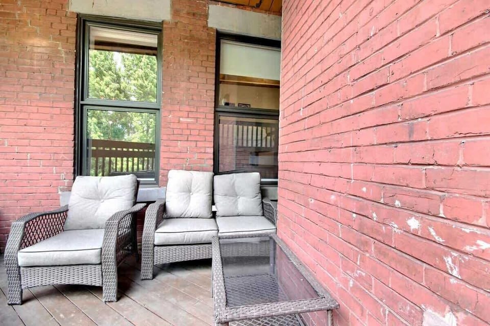 Charming balcony with a rustic brick wall and comfortable seating, ideal for relaxing and enjoying the fresh air.