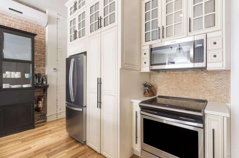 Modern kitchen featuring a white and brick design with vinyl wood flooring, blending warmth, style, and practicality seamlessly.