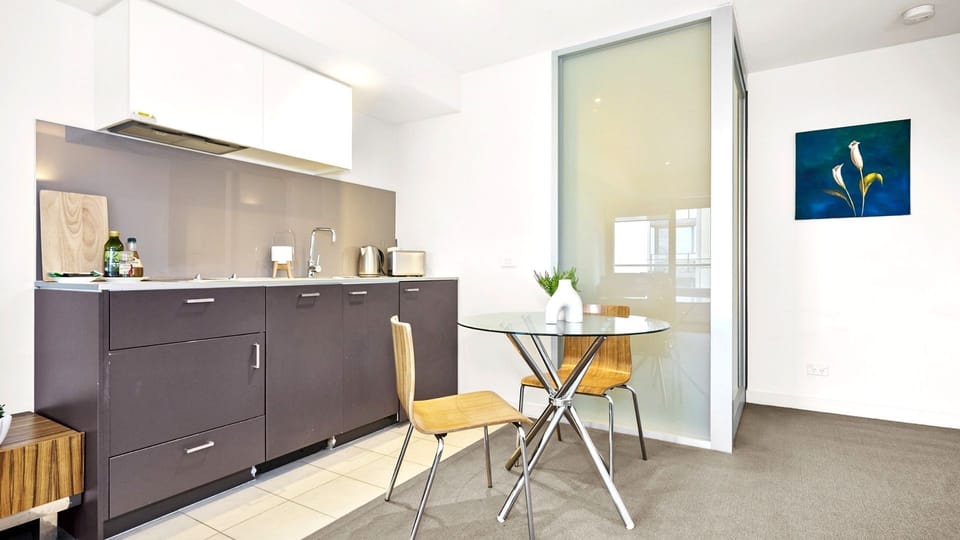 Streamlined dark cabinetry and a compact glass dining table maximize space.