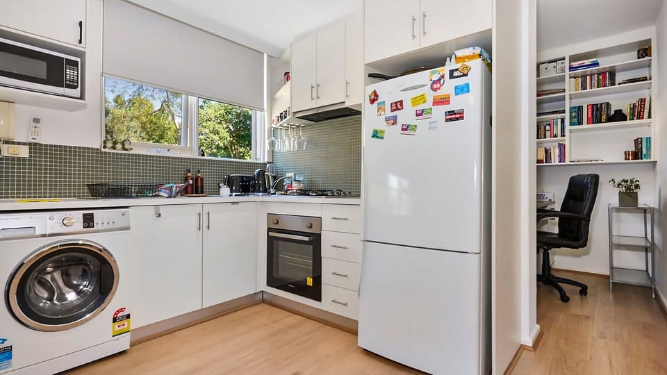Cook with ease in a modern u-shaped kitchen equipped with white cabinetry, a built-in oven, gas cooktop, and an integrated washing machine space.
