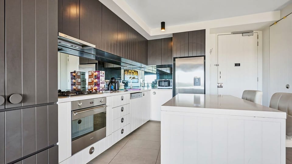 A brilliant perspective highlighting the functional layout and elegant white countertops of the kitchen.