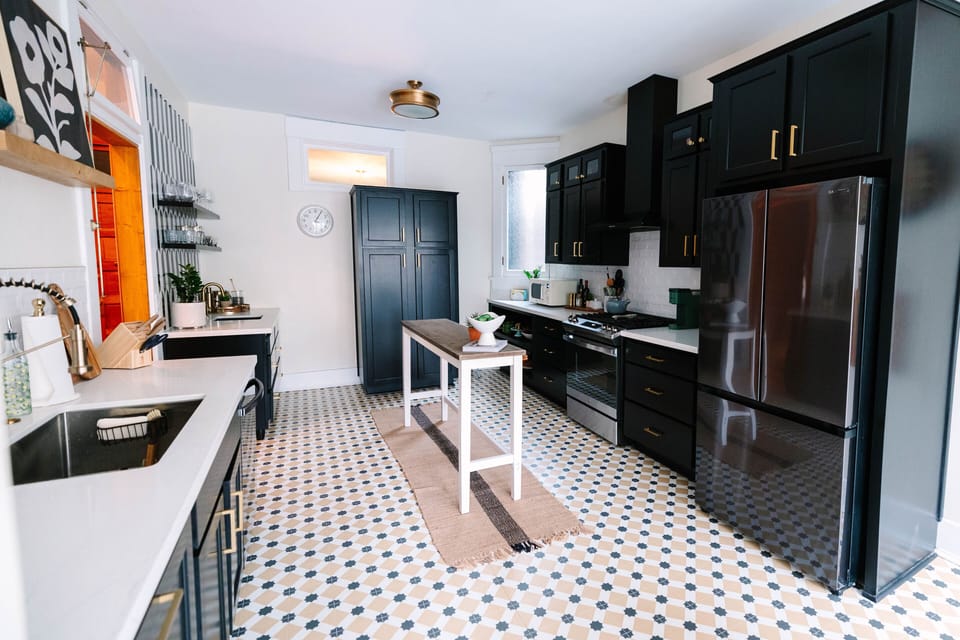 The kitchen features restored black cabinetry and white stone countertops for a sleek, modern look.
