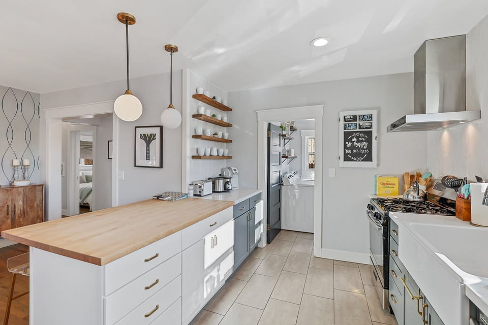 The kitchen features a gas stove, retro microwave, stainless steel appliances, and a charming farmhouse sink.