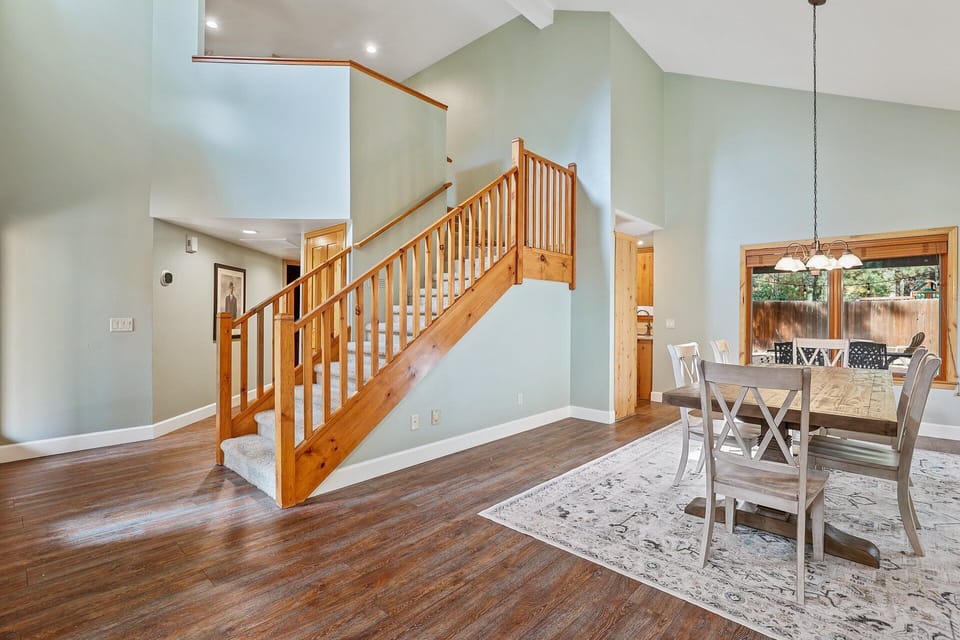 This home features a spacious open-concept interior with a wooden staircase, dining area, and large windows for natural light.