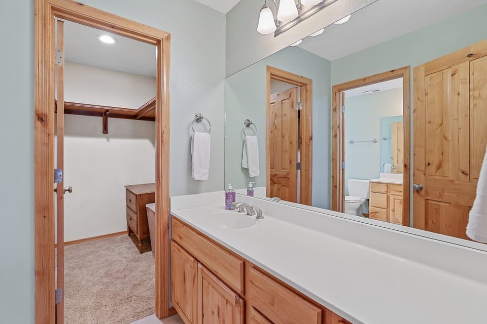 En suite with a jacuzzi tub, dual vanities, and walk-in shower.