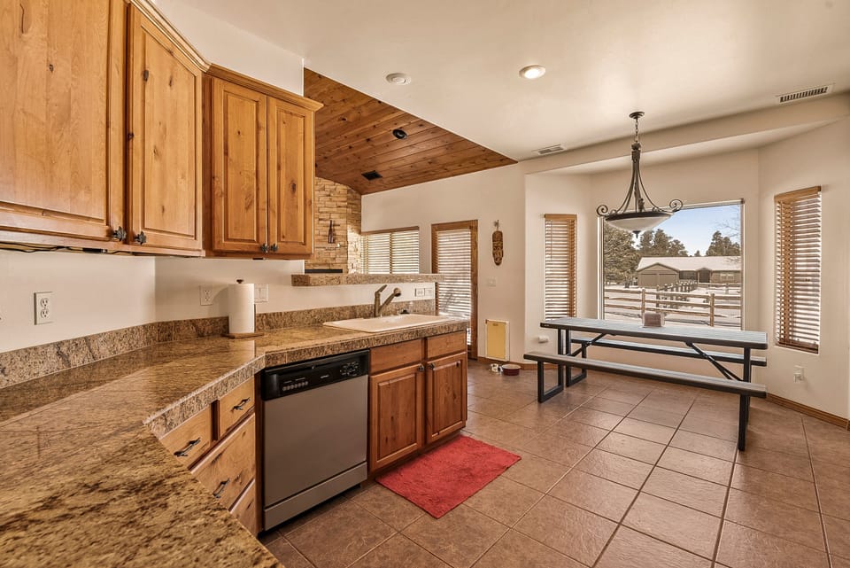 Serve meals at the breakfast bar or in the adjacent dining area, flooded with natural light from the surrounding wood-framed windows.
