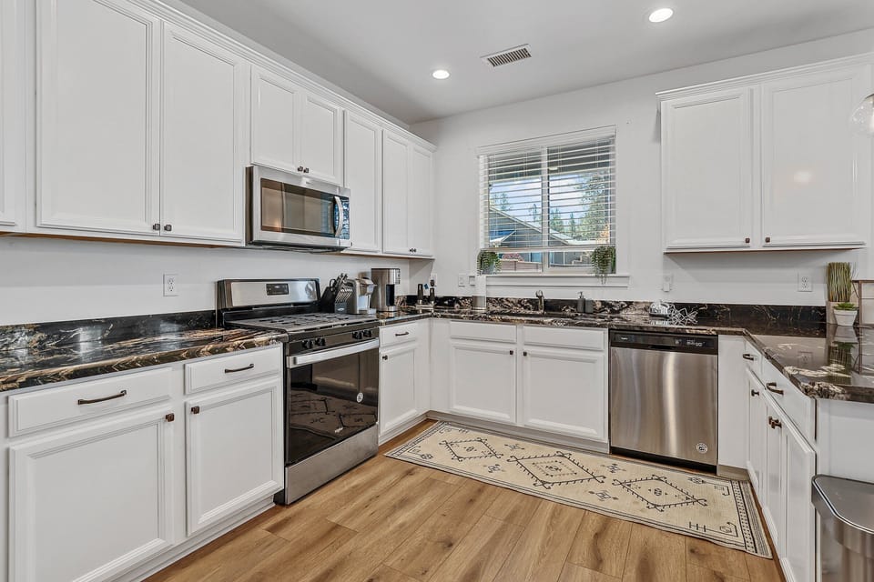 This chef's kitchen is a true showstopper, with dark granite countertops featuring cream swirls, ample cabinet and drawer space, and all the appliances you could need.