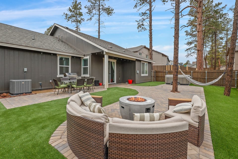 Outdoor firepit, seating, and a hammock in the large backyard.