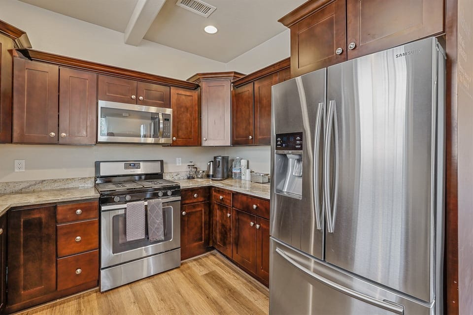 Create memorable meals in this fully equipped kitchen featuring premium appliances, dark wood cabinets, and ample counter space.
