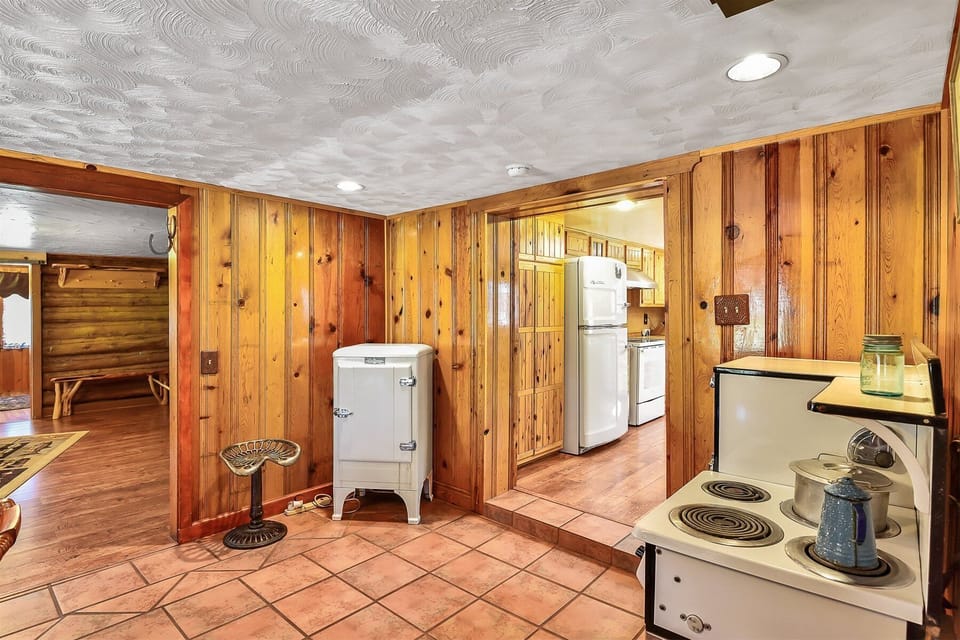 Adjacent is a large dining room with another table and vintage appliances, adding warmth and character while honoring the cabin's original era. This nostalgic touch creates a unique and memorable dining experience.