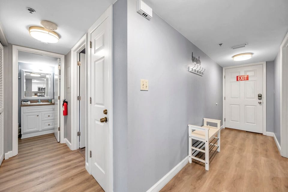 Clean hallway w/ wood floors & soft lighting, offering easy access to bedrooms & baths.
