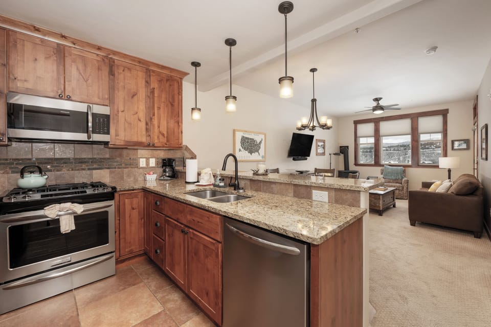 Step into your mountain retreat featuring a fully equipped kitchen with granite counters and warm wood cabinetry, perfectly flowing into the cozy living space.