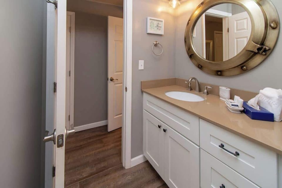 Modern bathroom vanity with a round nautical-style mirror and ample storage.