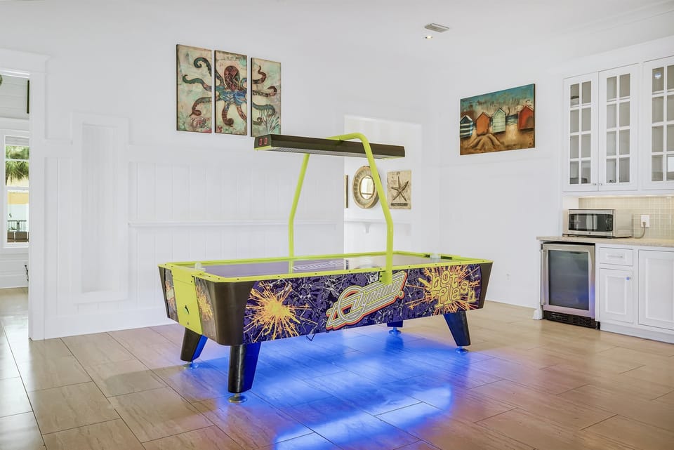 1st Floor - Game room with air hockey, custom arcades, 4K Smart TV, dining table, and a wet bar complete with mini fridge, ice maker, sink, and microwave