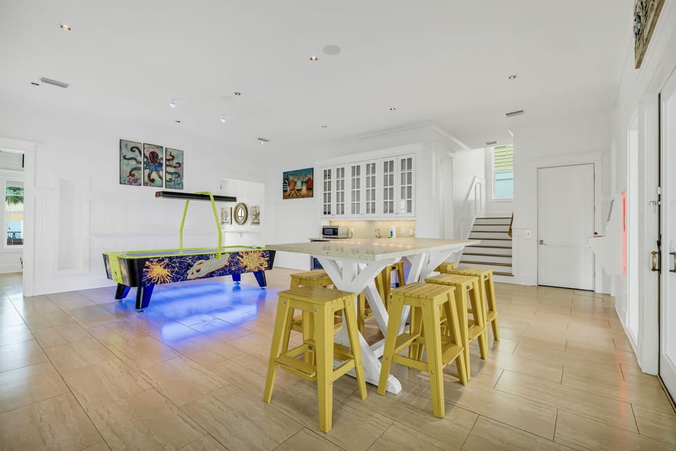 1st Floor - Game room with air hockey, custom arcades, 4K Smart TV, dining table, and a wet bar complete with mini fridge, ice maker, sink, and microwave