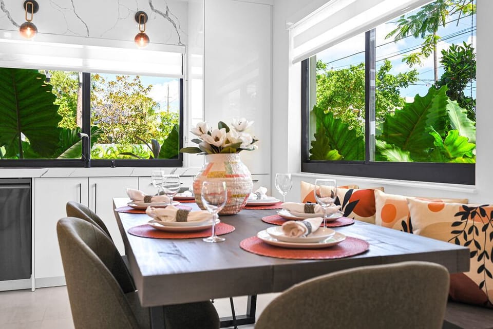 "Bright dining area with tropical views, vibrant table settings, and cushions."