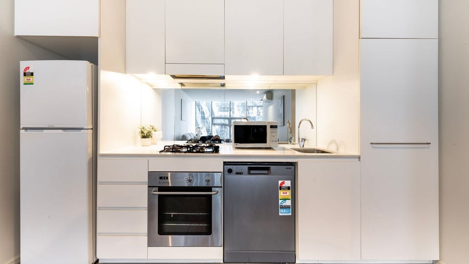 The contemporary kitchen is fully equipped with sleek white cabinetry and premium stainless steel appliances.