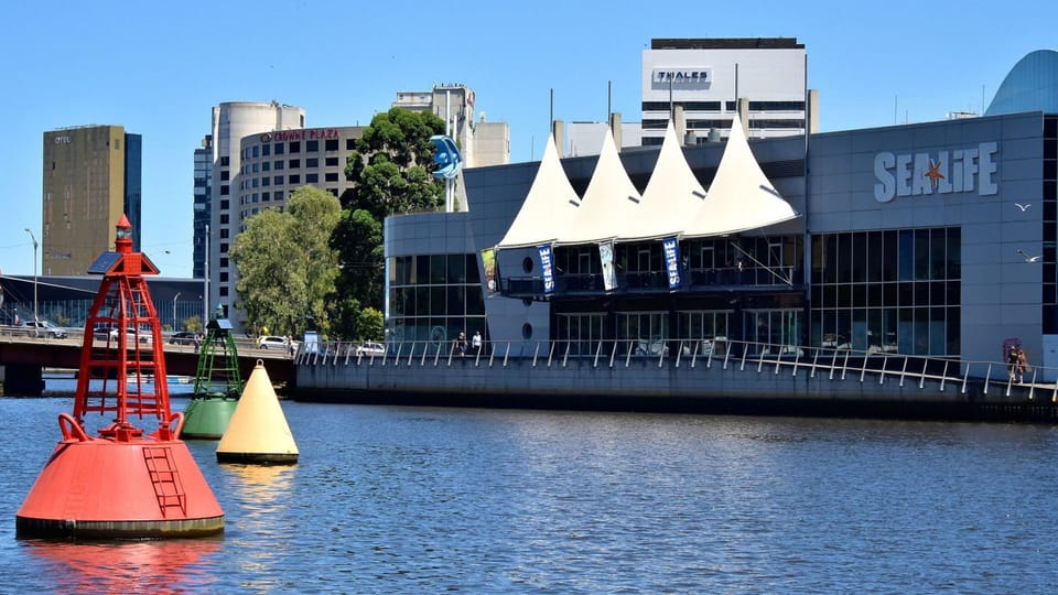 Colorful maritime buoys bob in the water right across from the iconic Sea Life Melbourne Aquarium building.