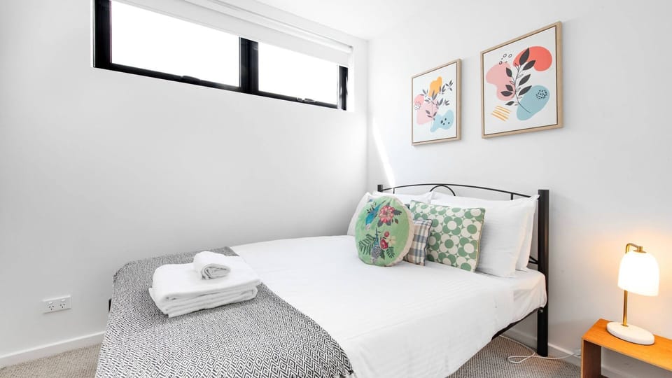 Elegant design meets cozy comfort in this bedroom, beautifully illuminated by high-set windows.