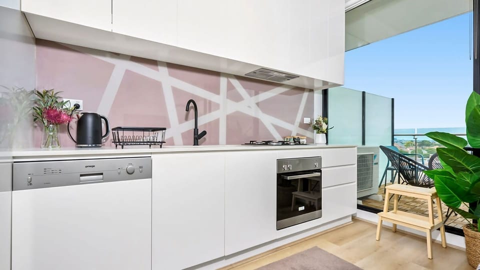 Cook with ease in a streamlined kitchen featuring modern appliances, white cabinetry, and a geometric-patterned splashback.