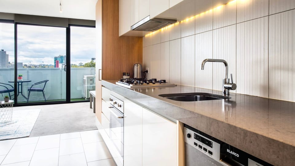 Contemporary kitchen featuring sleek finishes, stone benchtops, and city outlooks.