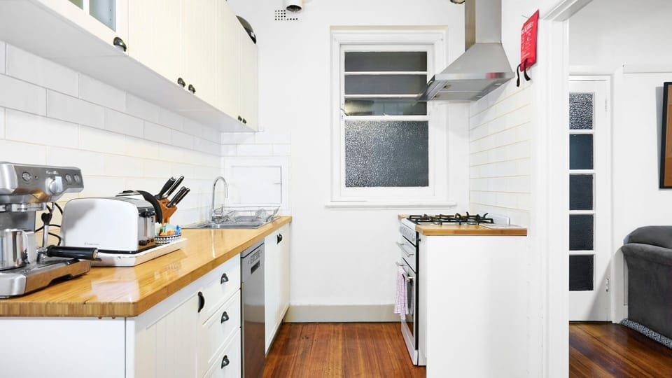 Cook with ease in a bright kitchen featuring warm timber countertops, modern appliances, and crisp white subway tiling.