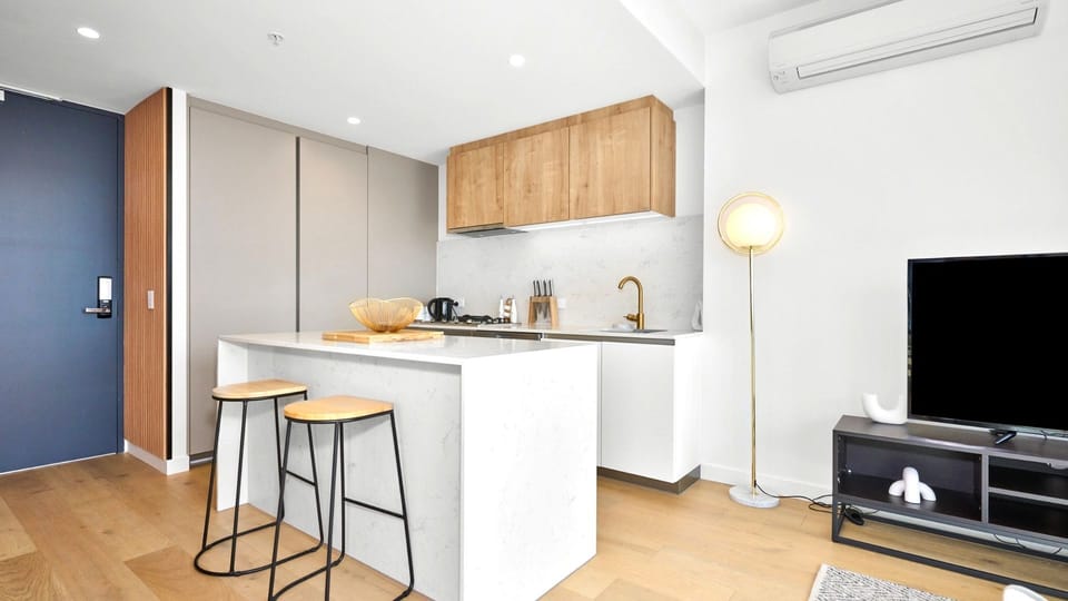 Sleek open-plan kitchen and living area with warm timber accents.