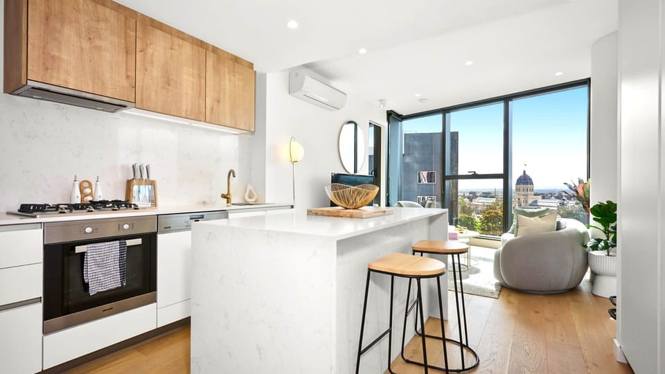 Modern kitchen flowing seamlessly into bright city-view living.