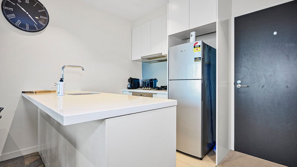 Sleek modern kitchen with stone benchtops, breakfast bar, and quality appliances.