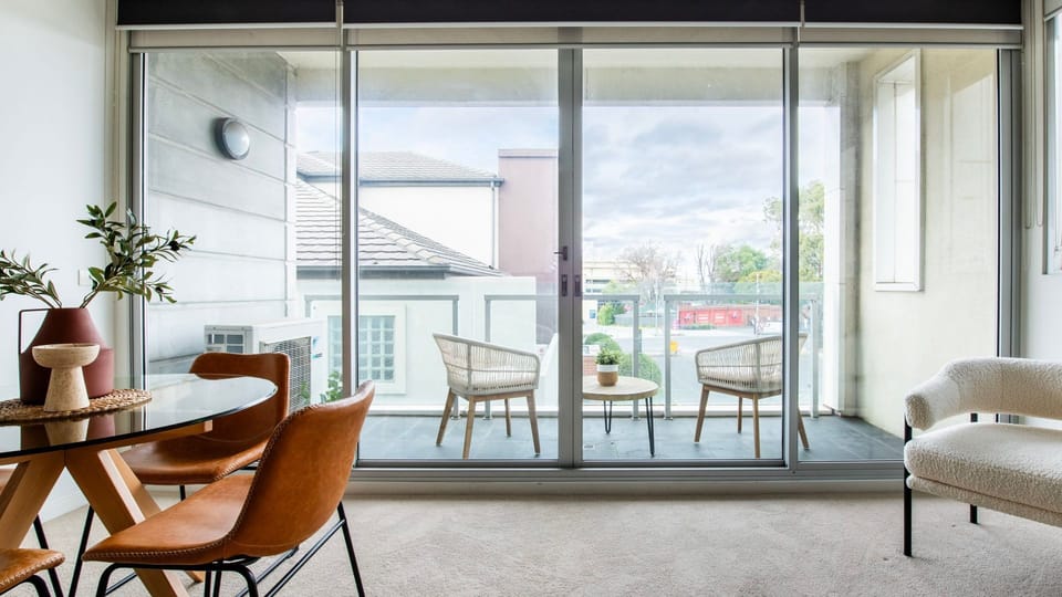 Massive floor-to-ceiling glass doors slide open to connect your main living area to a generous private balcony.