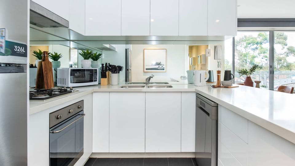 Another look at the highly functional cooking space, showcasing crisp cabinetry and sleek stone countertops.