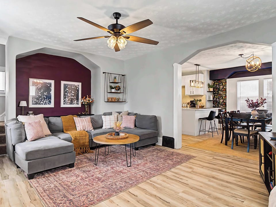Bright living room w/ vaulted ceiling, cozy seating, TV & warm wood floors for relaxing after a day out